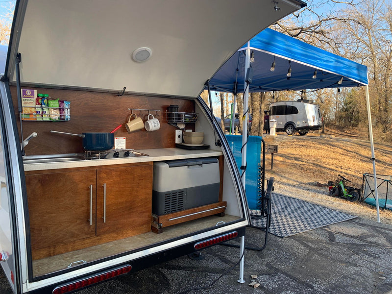  chairs|An open rv rental teardrop|A well-appointed RV rental|This rv rental's compact interior features a cozy grey bed — photo 5