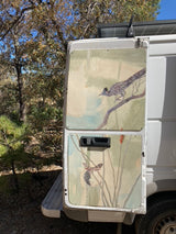 Explore nature with this unique RV rental featuring hand-painted roadrunner and moth art on its rear doors, parked outdoors.