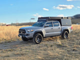 A grey Toyota Tacoma off-road truck with a rooftop tent and camper. Perfect for your next RV rental adventure!