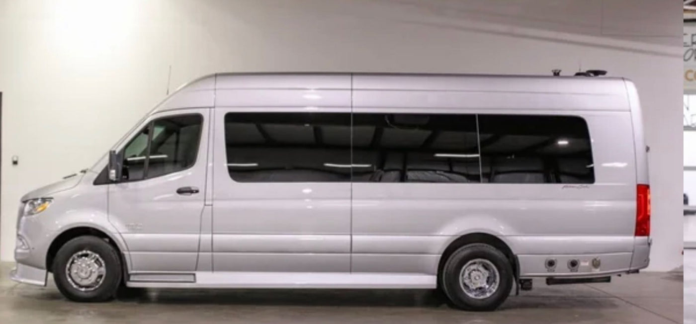 A silver Mercedes Sprinter RV rental. Side profile of a spacious, high-roof camper van in a showroom. — photo 2