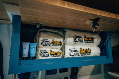 RV rental cabinet with H2O Therapy toiletries and "Scenic VANLIFE RENTALS" embroidered towels.
