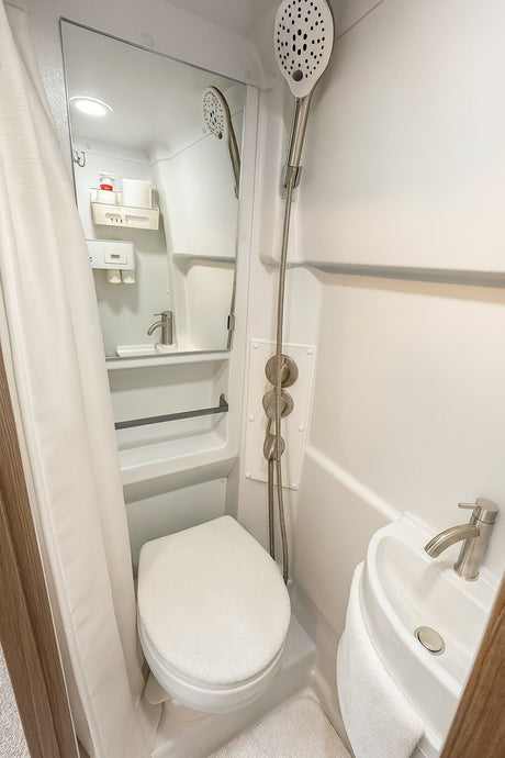 This RV rental's compact wet bath features a toilet, sink, and shower, optimizing space for comfortable travel adventures.