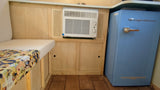 RV rental interior: Built-in AC unit, cozy bench with map cover, and a retro blue mini-fridge for comfortable travel.