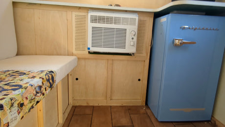 RV rental interior: Built-in AC unit, cozy bench with map cover, and a retro blue mini-fridge for comfortable travel.