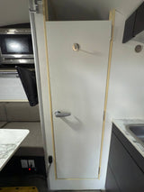 RV rental interior: kitchen with sink, microwave, dining booth with TV, and a central white door with a handle and hook.