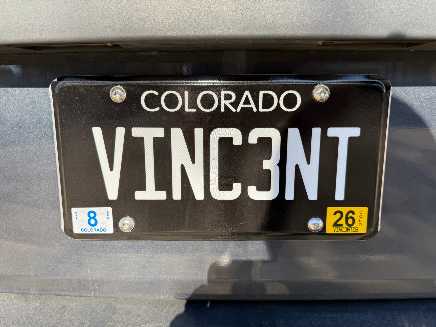 Colorado RV rental license plate "VINC3NT" with an August 2026 expiration sticker, seen on a vehicle's rear.