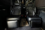Detailed view of two plush black leather captain's chairs with diamond quilting and footrests in an RV rental.
