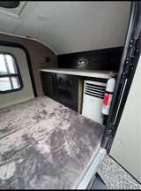 This compact rv rental offers a cozy bed, window, built-in storage, portable AC unit, and fire extinguisher for safety.