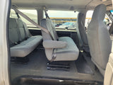Interior view of a passenger van for RV rental, showing grey multi-row seating with seatbelts.