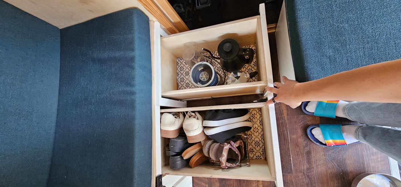RV rental: Pull-out storage drawers for kitchen essentials & shoes, maximizing space in a compact interior.