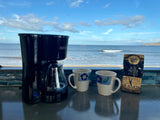 Morning coffee ritual in an RV rental, overlooking the ocean: Black+Decker brewer, mugs, and Royal Kona coffee.
