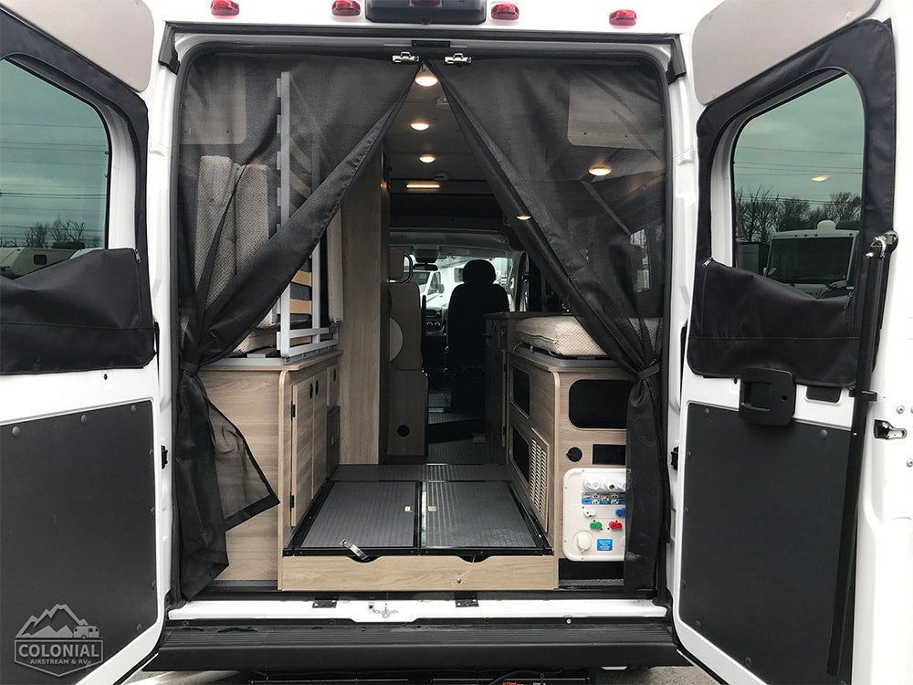  and passenger area. Perfect for adventures!|Versatile RV rental: Interior converts from dining table & bench to a full bed for comfortable sleep.|Cozy RV rental sleeping area: Colorful geometric comforter — photo 9