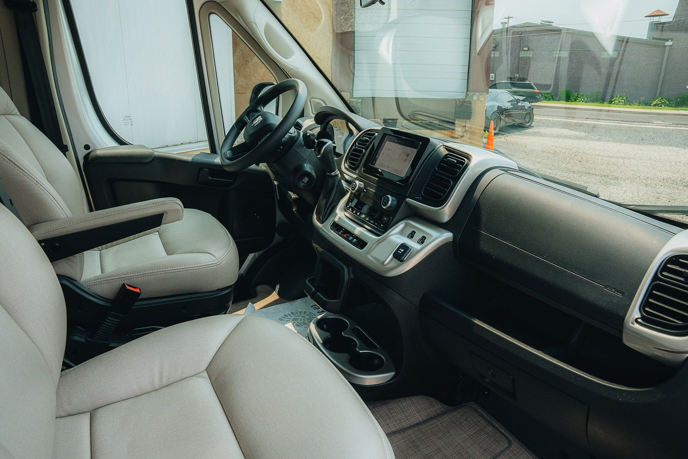 RV rental's spacious van interior: comfy driver & passenger seats, modern dashboard, and outside road view.