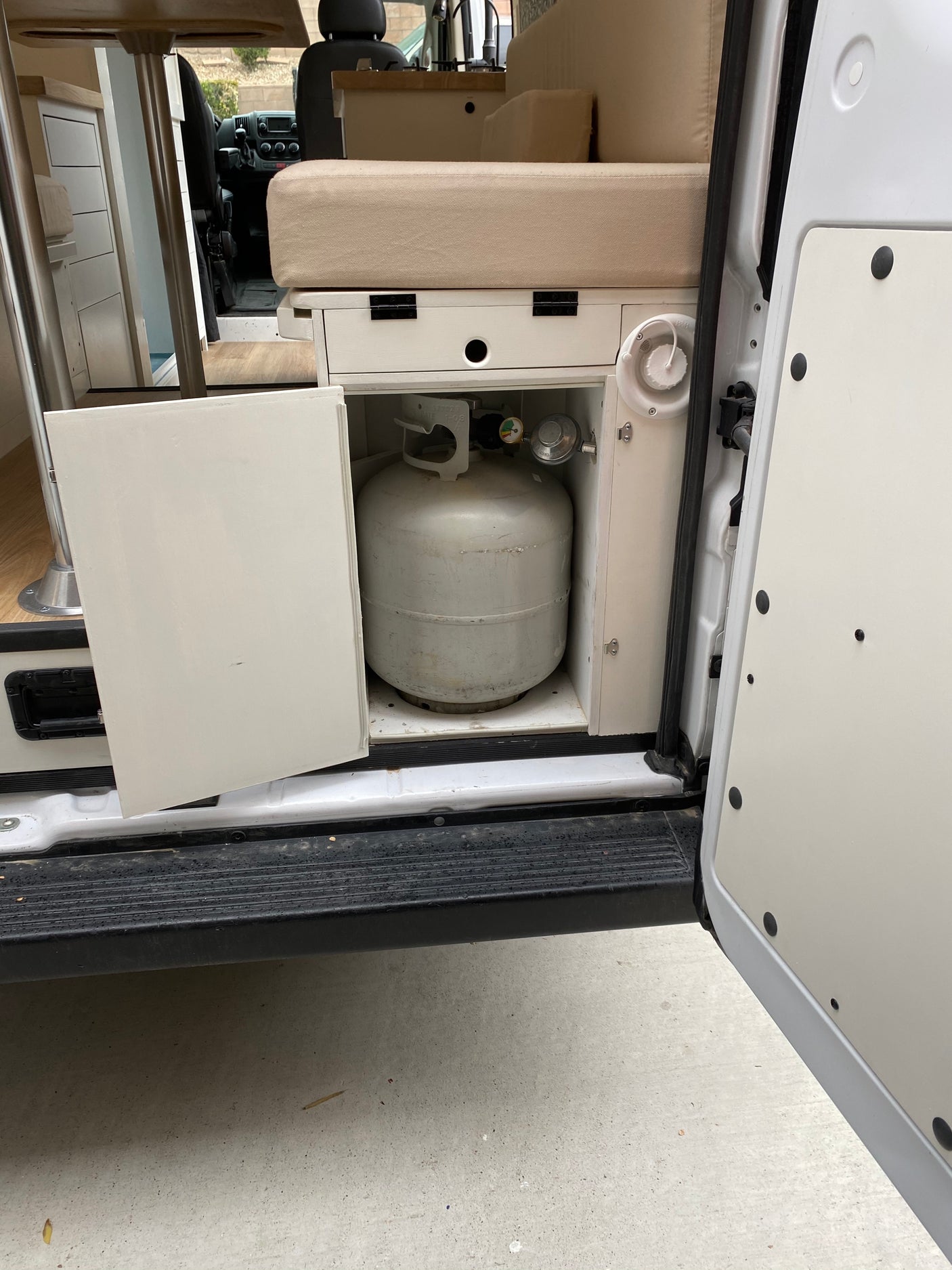 RV rental interior: open door reveals a propane tank, and part of the cozy kitchen and seating area.