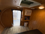 Inside a cozy **rv rental**: wood-paneled walls, AC unit, vinyl floor, and open door. Perfect compact camper setup.