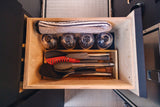 Compact kitchen organization for your RV rental adventure. Drawer with glasses, utensils, and a cozy blanket ready for the road.