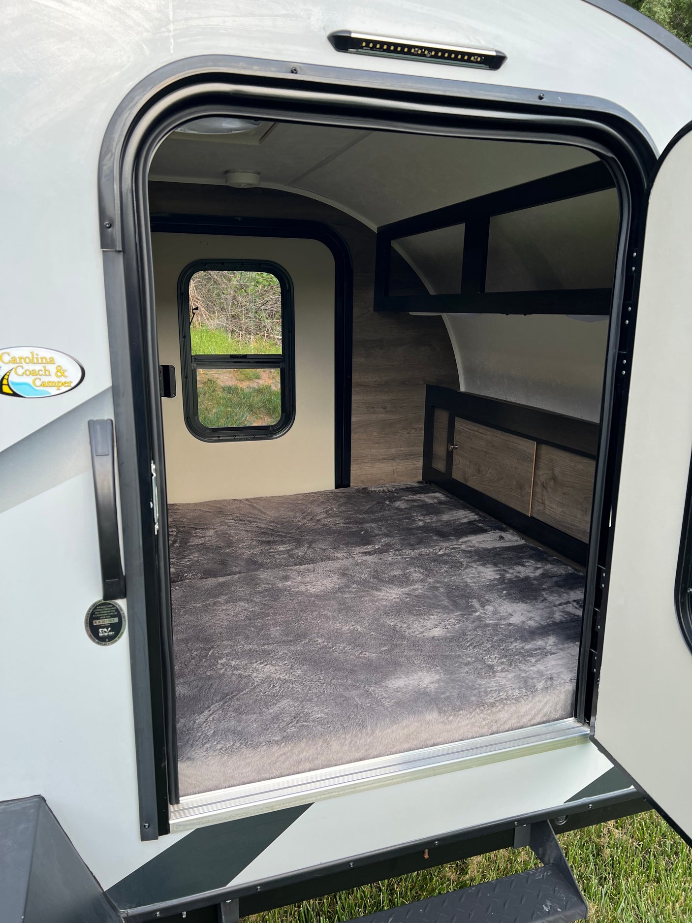 Step inside this cozy rv rental: large bed, window, and storage visible through the open door.