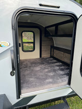 Step inside this cozy rv rental: large bed, window, and storage visible through the open door.
