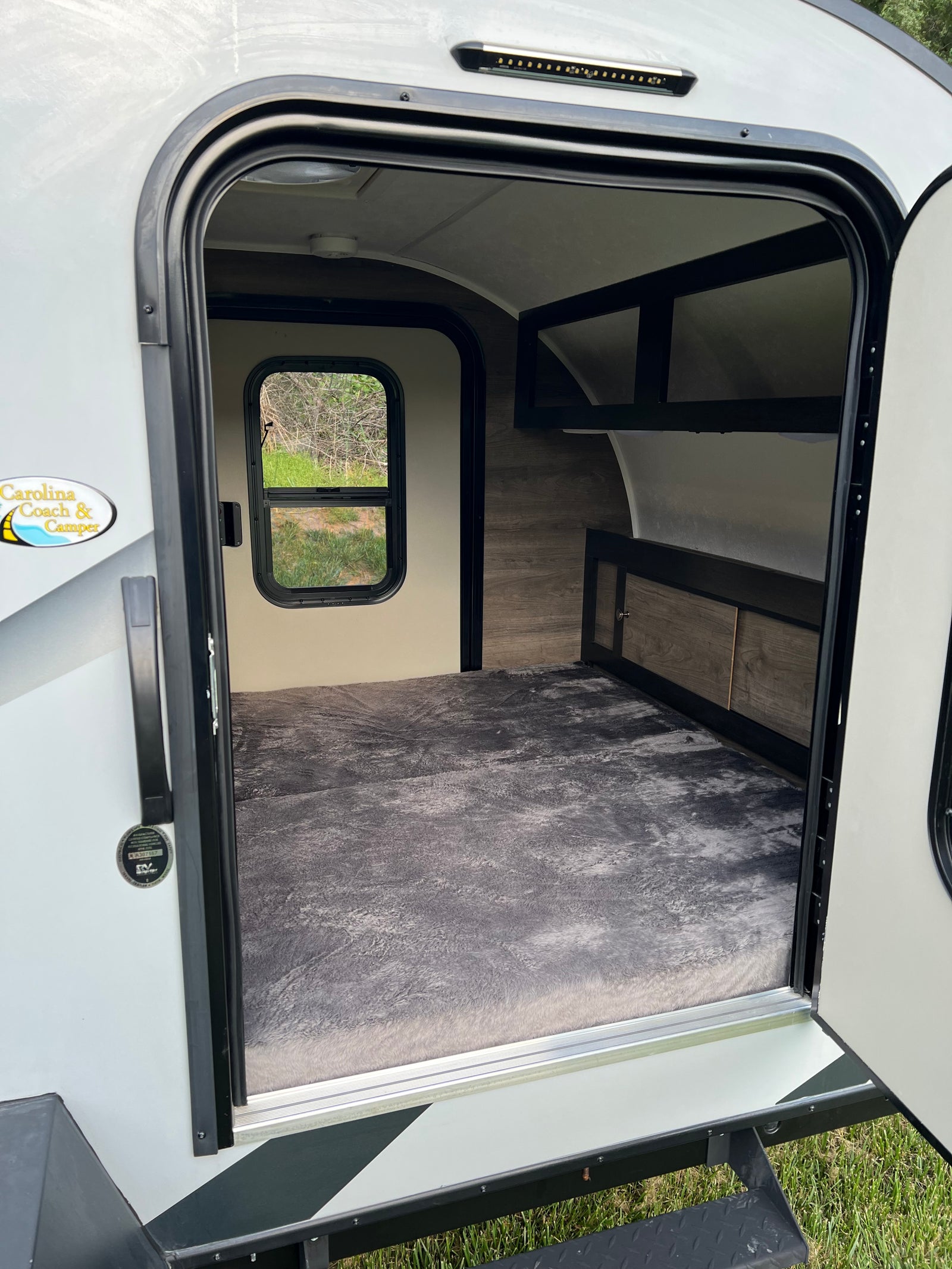 Step inside this cozy rv rental: large bed, window, and storage visible through the open door.