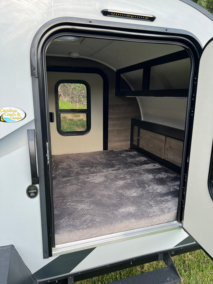 Step inside this cozy rv rental: large bed, window, and storage visible through the open door.