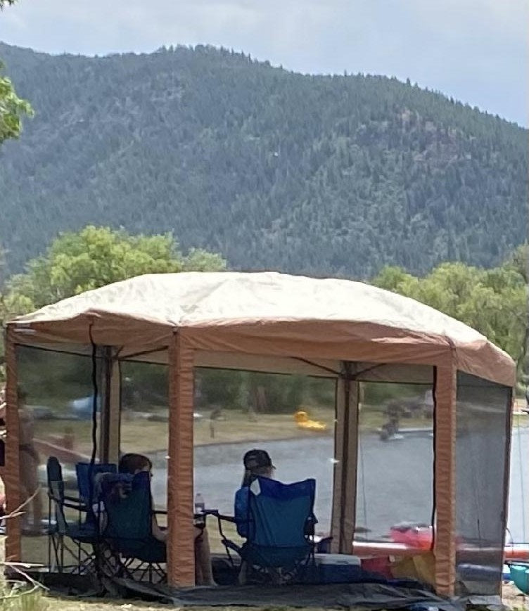  parked amidst mountains & rocks. Ideal for outdoor adventures.|This small white and black 'Outbound Extreme' teardrop camper with an extended awning is perfect for an rv rental adventure.|Enjoy lake views from your screened gazebo on an **rv rental** trip. People relax by the water with mountains in the background.|Three young people kayaking on a scenic mountain lake. Perfect outdoor recreation for an RV rental trip!|An RV rental with an attached tent setup on grass and pavement under a blue sky — photo 3