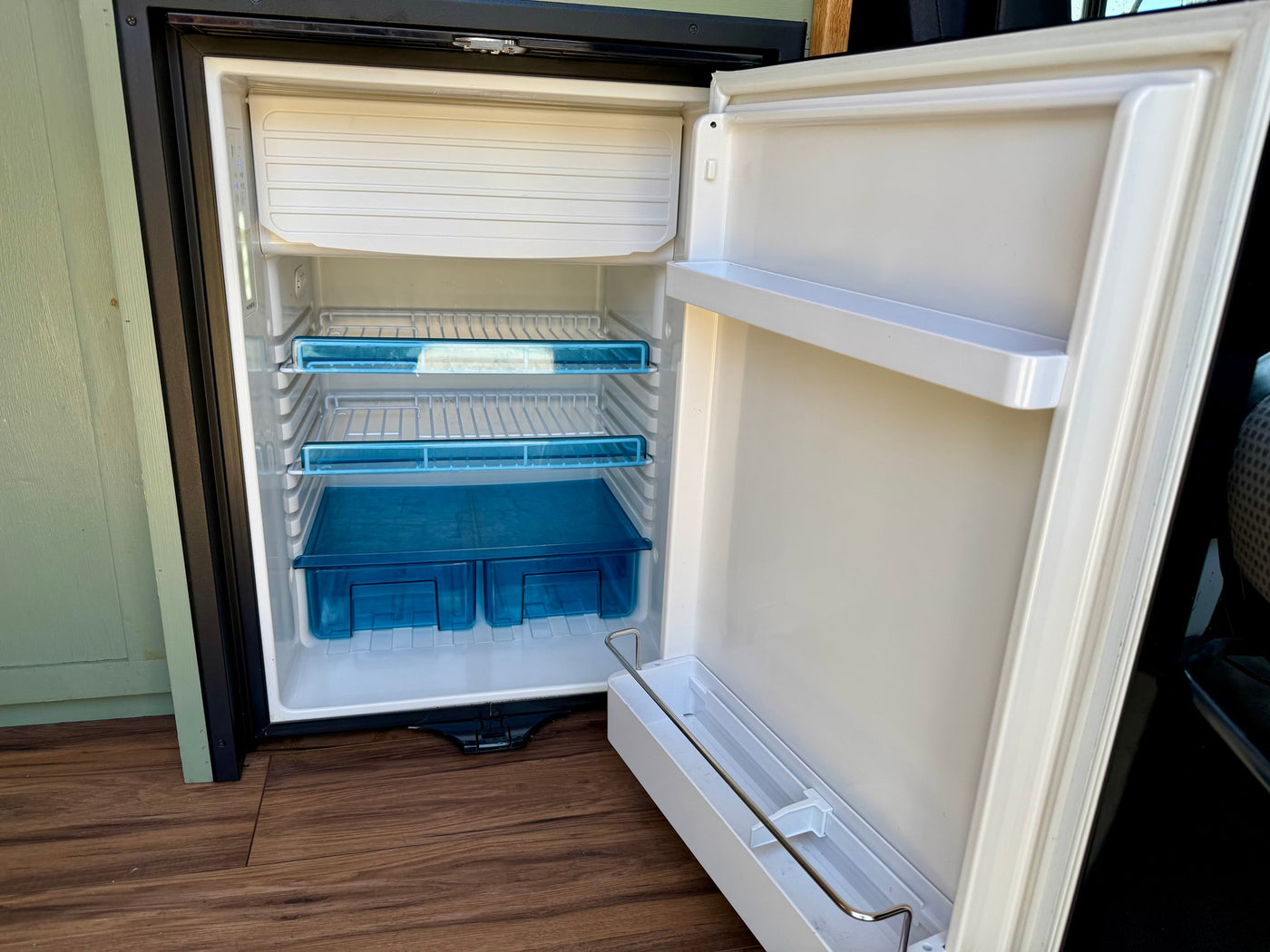 Inside an RV rental: a clean, compact Dometic refrigerator/freezer with shelves and door storage, ready for your journey. — photo 15