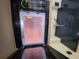 Open microwave in RV rental kitchen, showing control panel, turntable, and illuminated interior. Features a compact counter with sink.