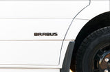 White custom RV rental side view, featuring a BRABUS emblem and all-terrain tire.