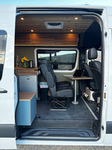 Discover this stylish rv rental van conversion interior, featuring a kitchen, swivel chairs, and a comfortable workspace.