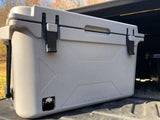 A light grey 50-quart cooler with black latches, made in USA, in a truck bed, ready for an rv rental adventure.