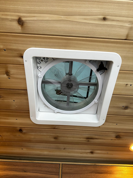 RV rental with a ceiling-mounted ventilation fan. Features include wood paneling & controls for airflow, temp, & open/close.