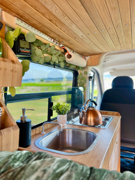 Experience van life: rv rental campervan kitchen with wood accents, sink, stove, & scenic views. Cozy interior!