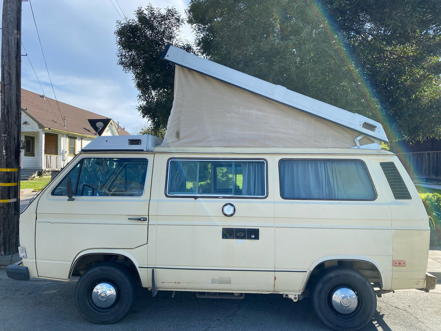 A cream VW Westfalia camper van with pop-top extended, ideal for an RV rental adventure on a sunny day.