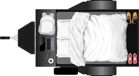 Overhead view of an RV rental's organized interior: bed with white linens, side table with laptop, backpack, coffee, and shoes.
