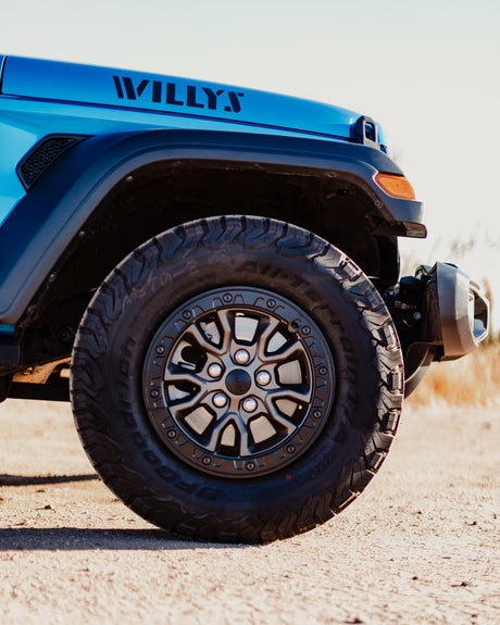 Blue Jeep Willys, with rugged BFGoodrich All-Terrain tires, poised for adventure. Ideal for an rv rental outdoor escape!