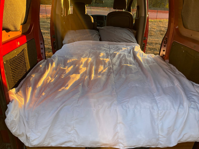 Experience comfort in this cozy rv rental! Van interior with a made bed, white comforter, and sunlit pillows. — photo 3