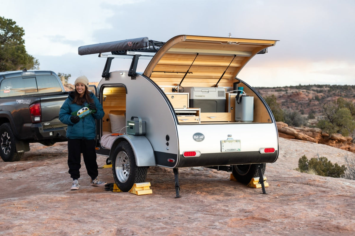 A smiling woman with her RV rental teardrop camper