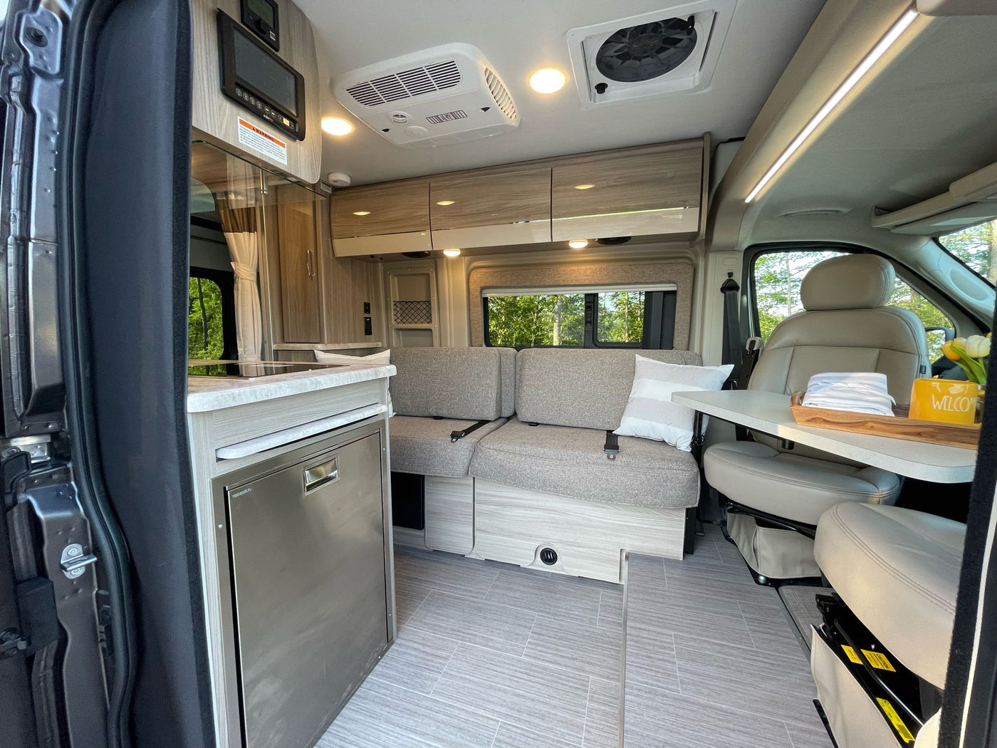 Modern RV rental interior: kitchen, flexible seating with table, swiveling front seats, and ample storage in a camper van. — photo 10
