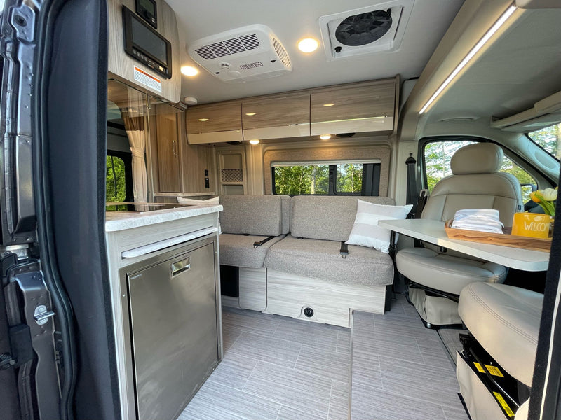 Modern RV rental interior: kitchen, flexible seating with table, swiveling front seats, and ample storage in a camper van. — photo 10