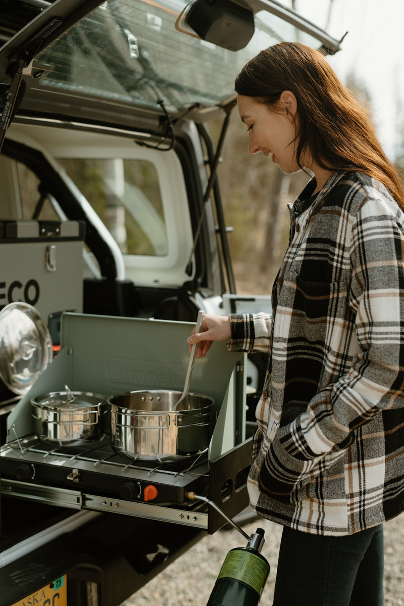 A woman prepares a meal using a camp stove pulled from her RV rental, highlighting the convenience of outdoor cooking. — photo 20