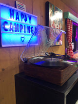 Cozy rv rental interior: 'Happy Camping' light-up sign & record player create a relaxed ambiance.