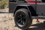 Close-up of a rugged off-road rv rental trailer's wheel, highlighting its all-terrain tire and diamond plate body.