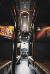 This luxury RV rental interior boasts plush seating and dual screens playing movies/Netflix for ultimate travel comfort.