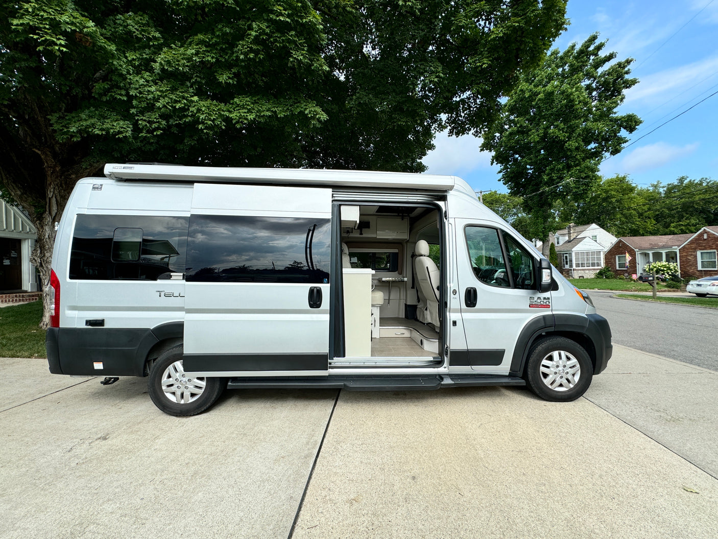 This silver RV rental with its side door open shows a bright interior, perfect for travel and road trip adventures.