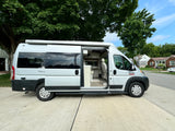 This silver RV rental with its side door open shows a bright interior, perfect for travel and road trip adventures.