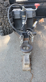 Hitching system of an RV rental trailer showing the heavy-duty pintle hitch, CURT jack, spare tire, and safety chains.