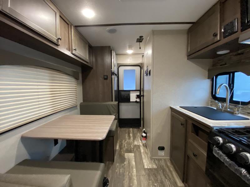  surrounded by tall trees.|RV rental interior showcasing a compact kitchen area with a sink