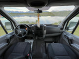 Dashboard perspective inside an RV rental, overlooking a scenic lake and mountains. Features steering wheel, dash, and front seats.