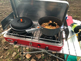RV rental adventure! Enjoying a hot meal cooked outdoors on a portable camping stove. Perfect for road trips and nature.