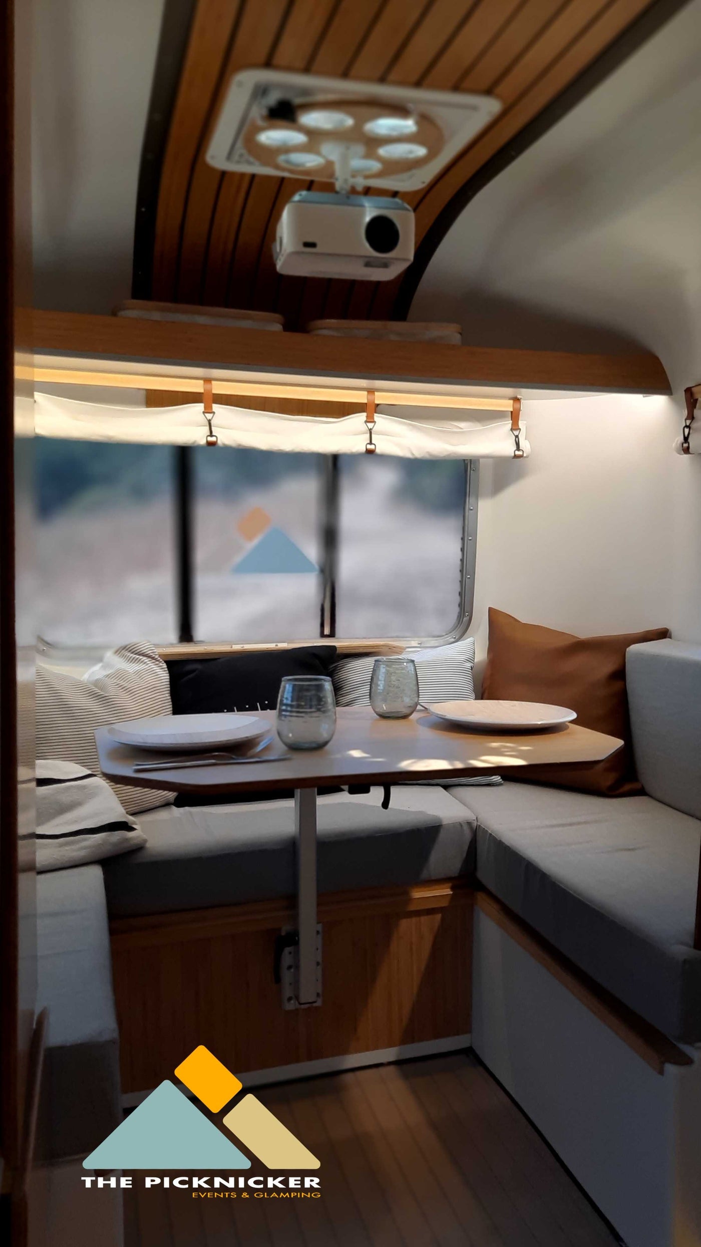 Cozy RV rental interior with a dining nook and projector. Perfect for comfortable glamping adventures with a view. — photo 6